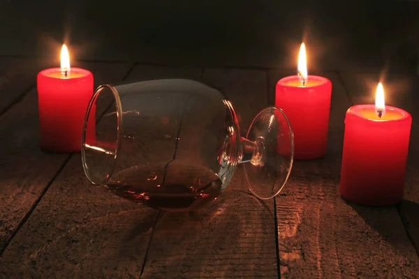 Glas Brandy oder Cognac und Kerze auf dem Holztisch. Festkomposition. — Stockfoto