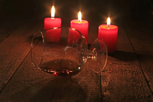 Vaso de brandy o coñac y vela sobre la mesa de madera. Composición de la celebración . —  Fotos de Stock