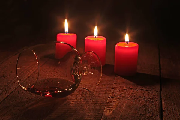 Glass of brandy or cognac and candle on the wooden table. Celebration composition. — Stock Photo, Image