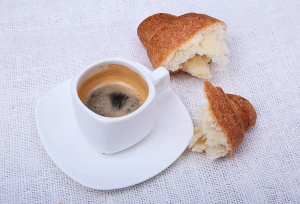 Хрустящие свежие круассаны и чашка кофе эспрессо на белом фоне, утренний завтрак, избирательный фокус — стоковое фото