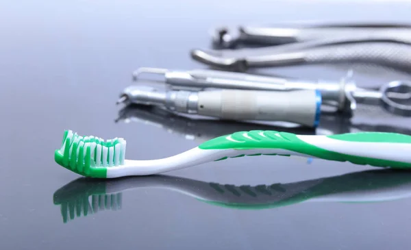 Cepillo dental con herramientas de dentista sobre fondo espejo . — Foto de Stock