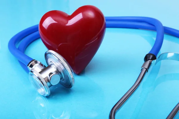 Stetoscopio medico e cuore rosso isolato su sfondo blu specchio — Foto Stock