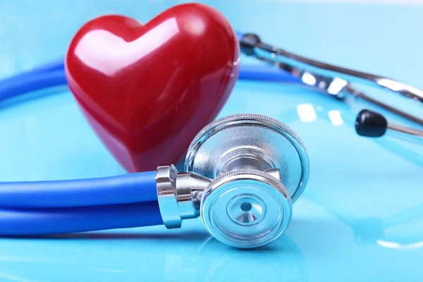 Estetoscopio médico y corazón rojo aislados sobre fondo de espejo azul — Foto de Stock