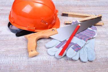 Turuncu kask, koruyucu gözlük, eldiven ve ahşap arka plan üzerinde ölçüm bandı.