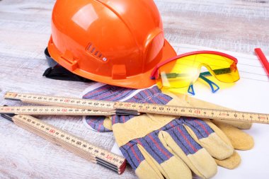 Turuncu kask, koruyucu gözlük, eldiven ve ahşap arka plan üzerinde ölçüm bandı. metninizi yerleştirebilirsiniz