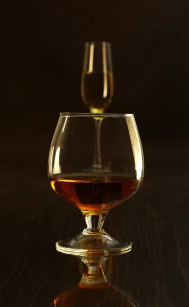 İki bardak brendi veya konyak ve siyah arka plan üzerine şişe — Stok fotoğraf