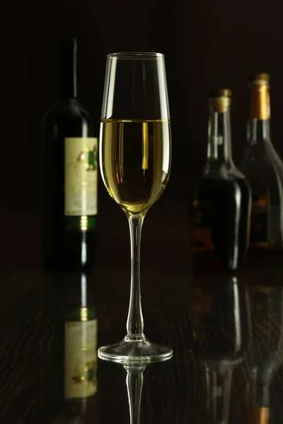 Glas vin och en flaska på en svart spegel bakgrund — Stockfoto