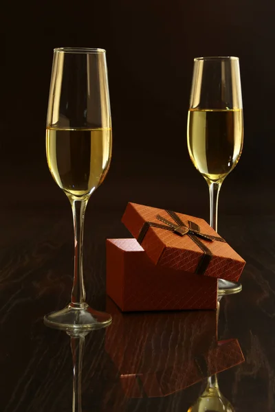 Two glasses with white wine and gift box on mirror table. Celebrities composition. Your text here. — Stock Photo, Image