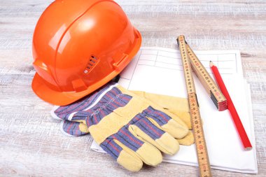 Turuncu kask, koruyucu gözlük, eldiven, kalem ve ahşap arka plan kasette ölçme.
