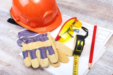 Turuncu kask, koruyucu gözlük, eldiven, kalem ve ahşap arka plan kasette ölçme.
