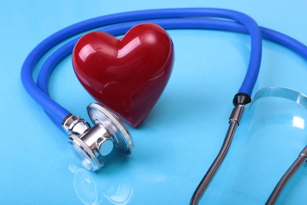 Stetoscopio medico e cuore rosso isolato su sfondo blu specchio . — Foto Stock