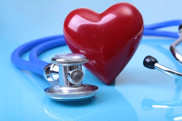 Estetoscópio médico e coração vermelho isolado no fundo do espelho azul . — Fotografia de Stock