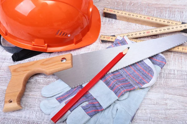 Orange hard hat, Earplug to reduce noise, safety glasses, gloves, pen and measuring tape on wooden background. Stock Image