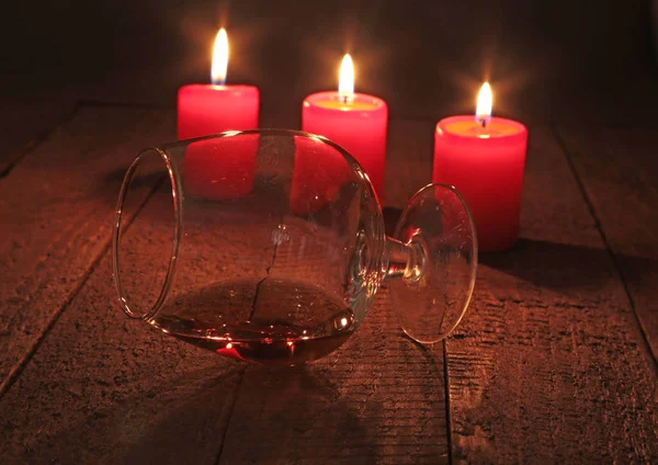 Glass of brandy or cognac and candle on the wooden table — Stock Photo, Image