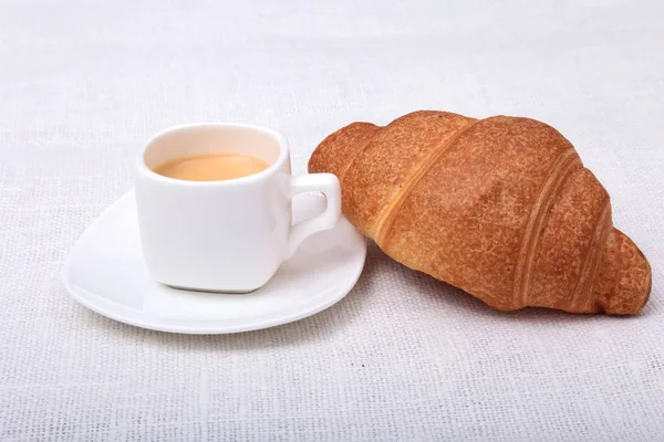 Knusprige frische Croissants und eine Tasse Kaffee-Espresso auf weißem Hintergrund, Frühstück am Morgen, selektiver Fokus — Stockfoto