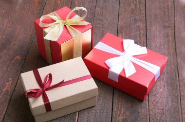 ahşap arka plan üzerinde kırmızı ve altın hediye kutusu.