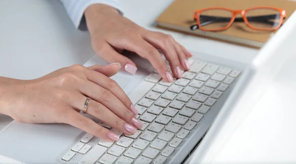 Жінка працює на ноутбуці, сидячи за столом — стокове фото