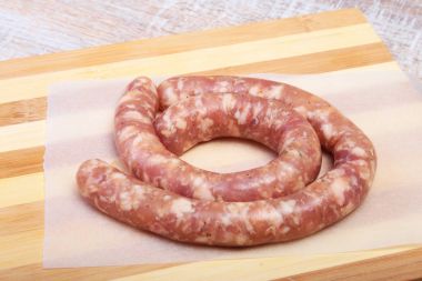 Ahşap arka plan üzerinde baharatlar ile ev yapımı çiğ sosis.