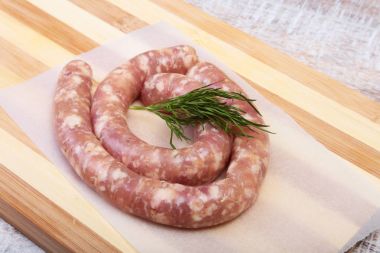 Ahşap arka plan üzerinde baharatlar ile ev yapımı çiğ sosis.