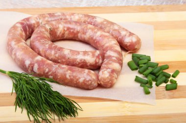 Ahşap arka plan üzerinde baharatlar ile ev yapımı çiğ sosis.