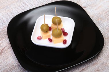 Peynirli kanepeler zeytin ve ahşap tepsi nar taneleri ile yakın çekim.