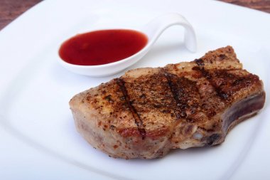 ızgara domuz eti ile kızılcık sosu ahşap tahta üzerinde plaka üzerinde