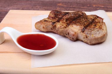 ızgara domuz eti ile kızılcık sosu ahşap tahta üzerinde plaka üzerinde