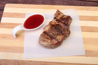 ızgara domuz eti ile kızılcık sosu ahşap tahta üzerinde plaka üzerinde