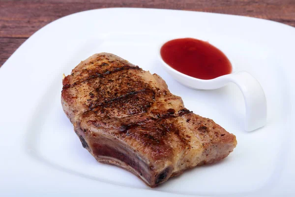 Chuleta de cerdo a la parrilla con salsa de arándano en plato sobre tabla de madera — Foto de Stock