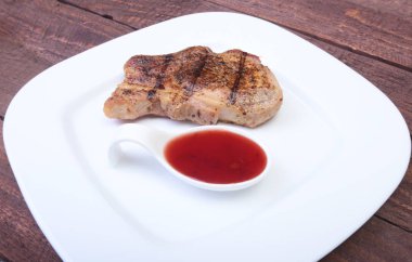 ızgara domuz eti ile kızılcık sosu ahşap tahta üzerinde plaka üzerinde