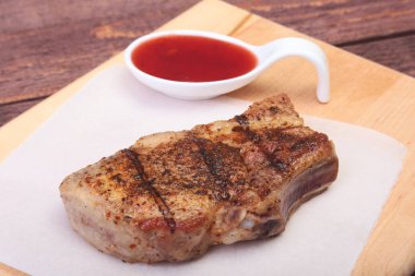 ızgara domuz eti ile kızılcık sosu ahşap tahta üzerinde plaka üzerinde