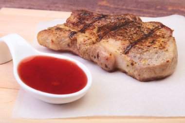 ızgara domuz eti ile kızılcık sosu ahşap tahta üzerinde plaka üzerinde