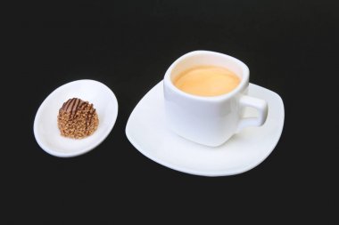Klasik espresso kahve ve pralin siyah arka plan üzerine beyaz fincan.