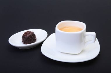 Klasik espresso kahve ve pralin siyah arka plan üzerine beyaz fincan.