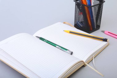 Açık boş sayfa defter ve kalem beyaz masada.