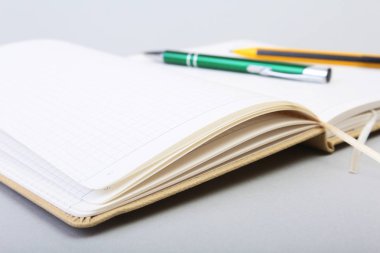Açık boş sayfa defter ve kalem beyaz masada.