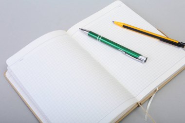 Açık boş sayfa defter ve kalem beyaz masada.