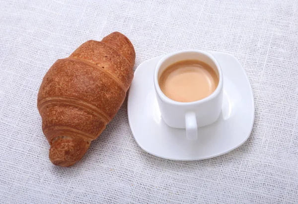 Croissants frescos crocantes e xícara de café expresso em um fundo branco, café da manhã, foco seletivo — Fotografia de Stock