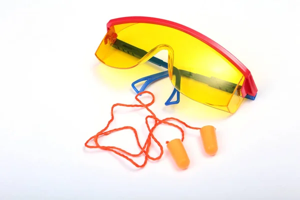 Orange öronpropparna och skyddsglasögon för arbete. Öronproppen att minska buller på en vit bakgrund . — Stockfoto
