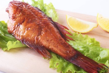 Füme balık ve beyaz arka plan üzerinde izole tahta kesme tahta üzerinde yeşil marul yaprakları limon.