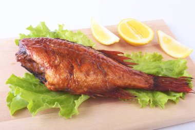 Füme balık ve beyaz arka plan üzerinde izole tahta kesme tahta üzerinde yeşil marul yaprakları limon.