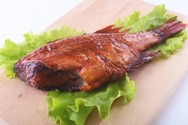 Füme balık ve beyaz arka plan üzerinde izole tahta kesme tahta üzerinde yeşil marul yaprakları limon.