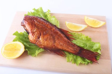 Füme balık ve beyaz arka plan üzerinde izole tahta kesme tahta üzerinde yeşil marul yaprakları limon.