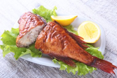 Füme balık ve beyaz arka plan üzerinde izole tahta kesme tahta üzerinde yeşil marul yaprakları limon.