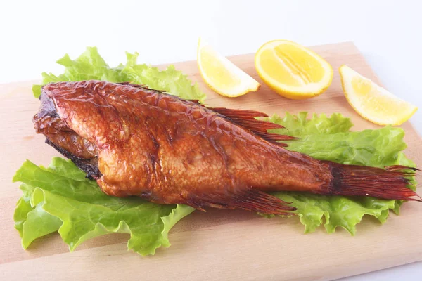 Füme balık ve beyaz arka plan üzerinde izole tahta kesme tahta üzerinde yeşil marul yaprakları limon.