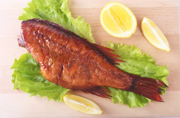 Pescado ahumado y limón sobre hojas de lechuga verde sobre tabla de cortar de madera aislada sobre fondo blanco . —  Fotos de Stock