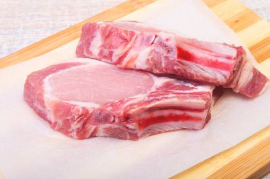 Çiğ domuz pirzolası, kesme tahtası üzerinde baharat. Hazır yemek pişirmek için.