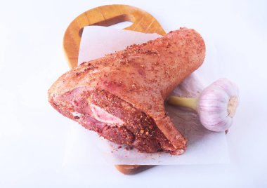 Çiğ domuz knuckle, sarımsak ve baharat bir kesme tahtası üzerinde. Seçici odak. Hazır yemek pişirmek için.