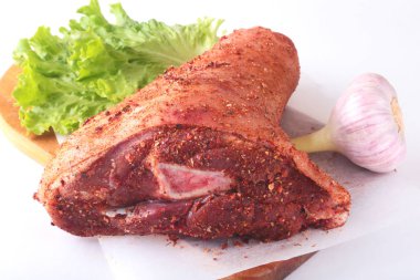 Çiğ domuz knuckle, sarımsak, baharat ve marul yaprakları bir kesme tahtası üzerinde. Seçici odak. Hazır yemek pişirmek için.