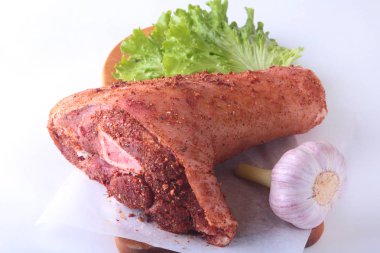 Çiğ domuz knuckle, sarımsak, baharat ve marul yaprakları bir kesme tahtası üzerinde. Seçici odak. Hazır yemek pişirmek için.
